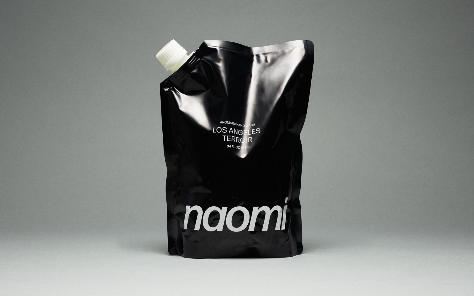 A bottle of amber-colored Naomi hand wash labeled 'Los Angeles Terroir' against a plain grey background.
