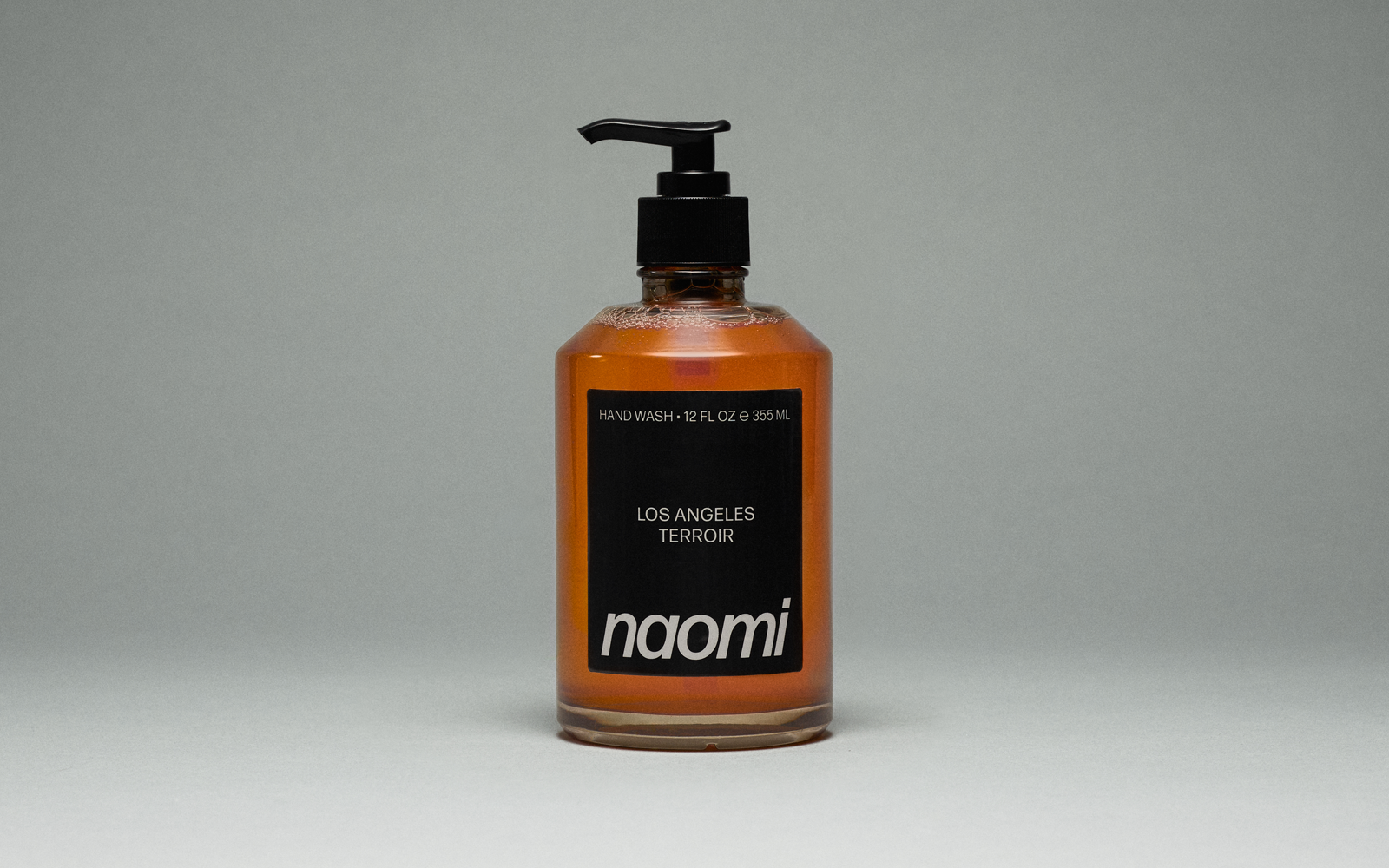 A bottle of amber-colored Naomi hand wash labeled 'Los Angeles Terroir' against a plain grey background.